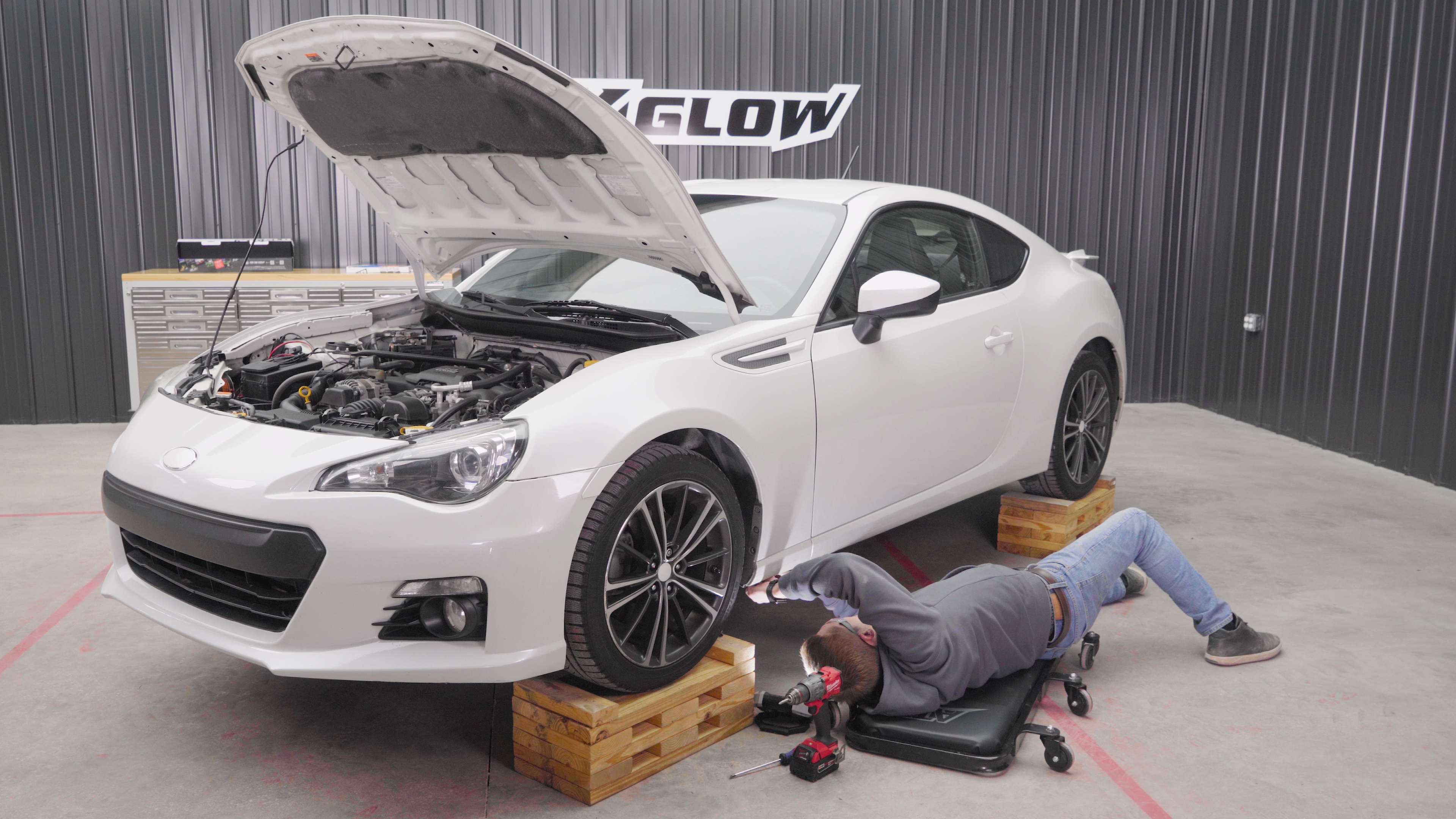 Riley from XKGLOW underneath a white Subaru BRZ, installing underglow.