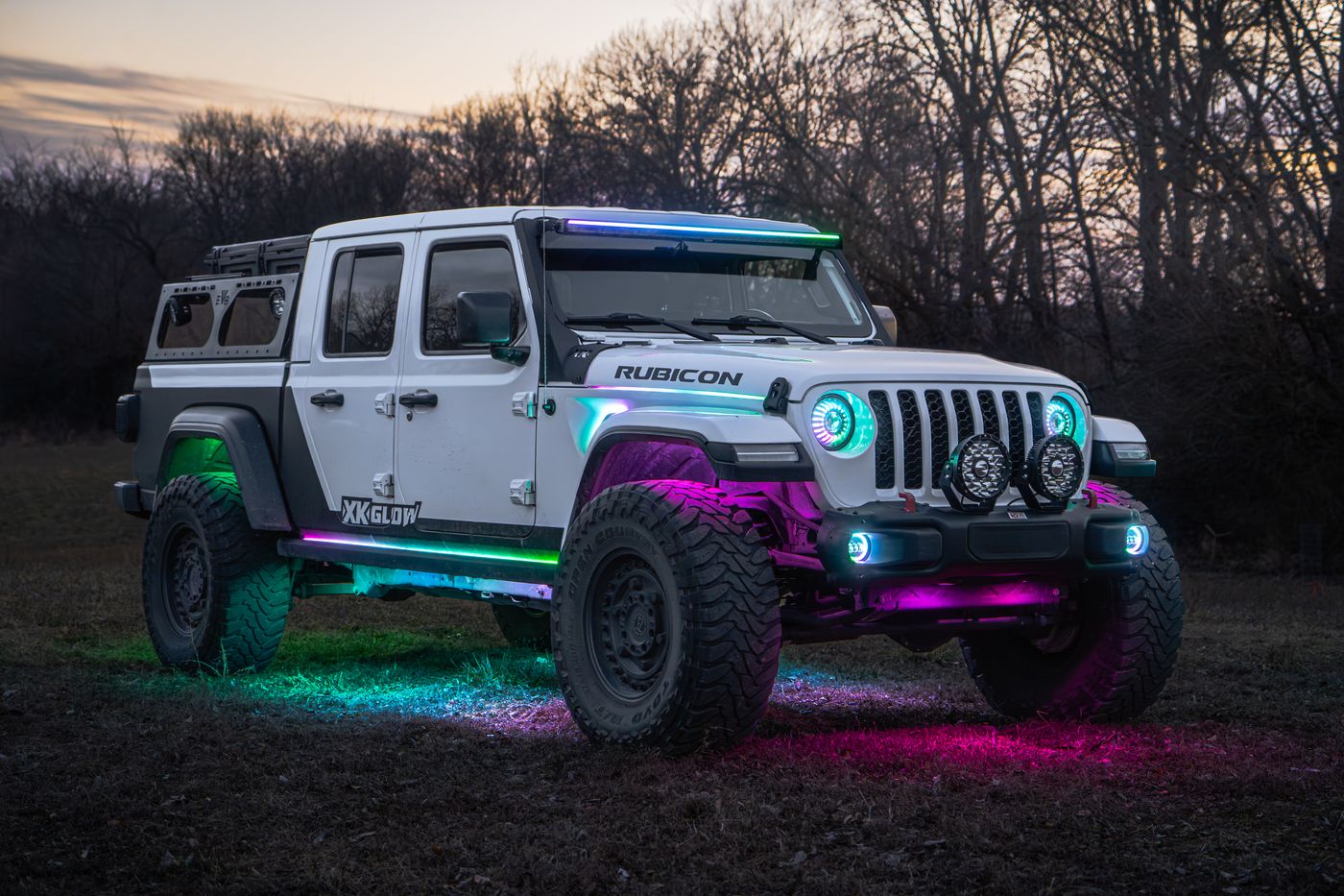 White Jeep Wrangler Rubicon with rock lights running two colors at once, green and pink, at dusk