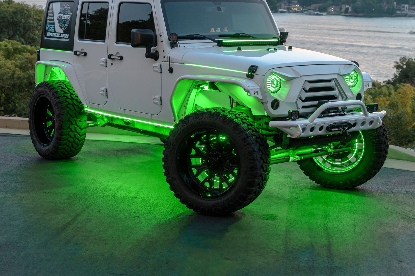 White Jeep Wrangler JK with green rock lights at dusk by the water