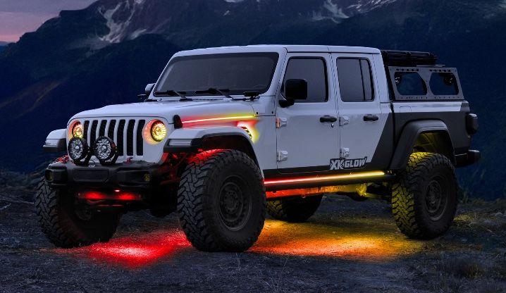 XKGLOW Jeep Gladiator at night with amber accent strips along the hood and running board, plus red underglow