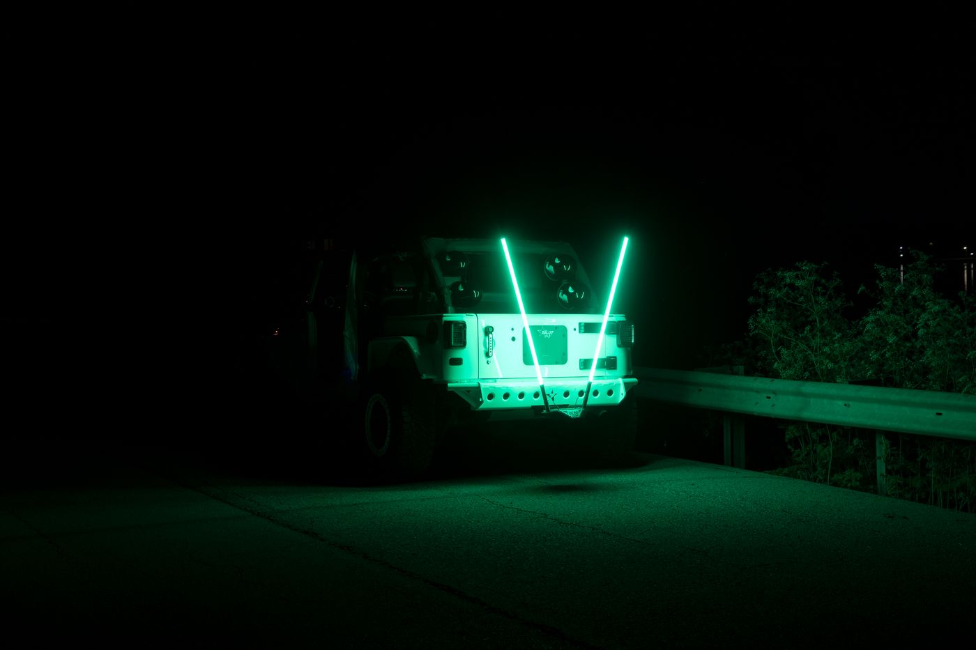 Two green LED whip lights mounted on a hitch receiver at night