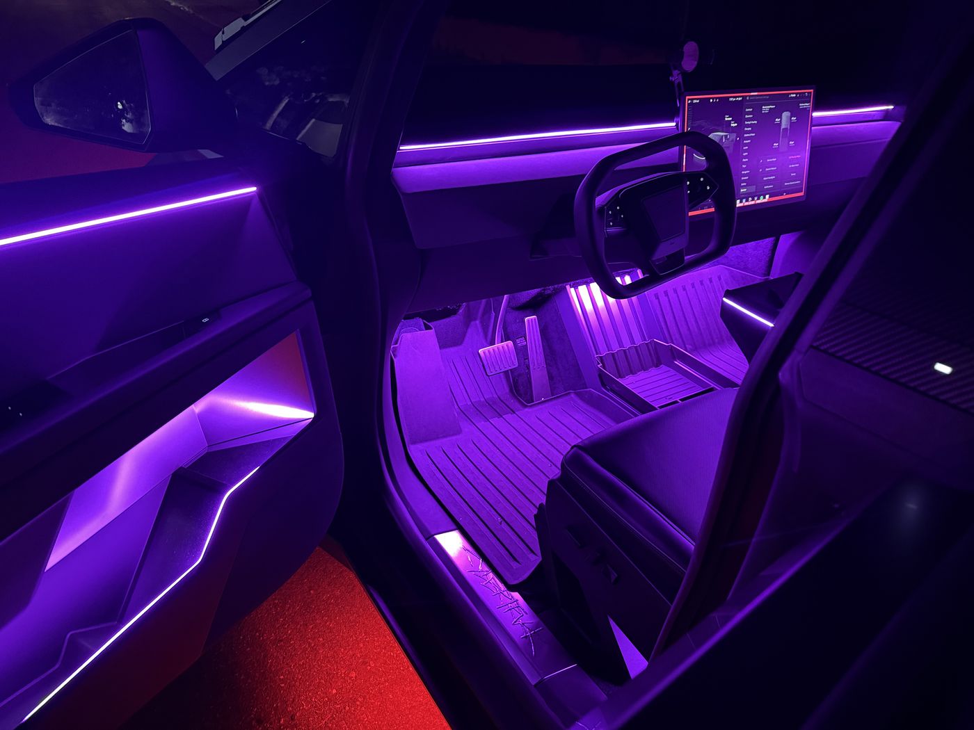 Tesla Cybertruck interior lit purple with fiber-optic ambient lighting on the doors and dash