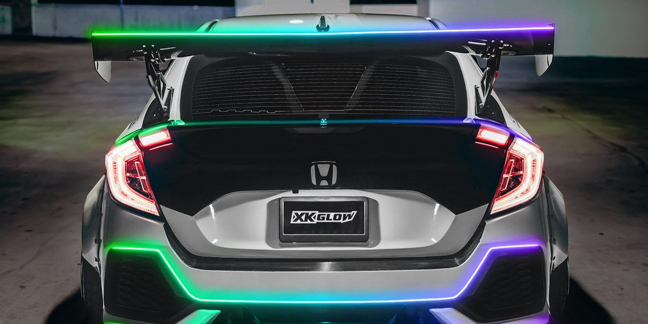 Rear of a silver hatchback with LED strips lit along the spoiler, trunk edge, and bumper in green, blue, and purple