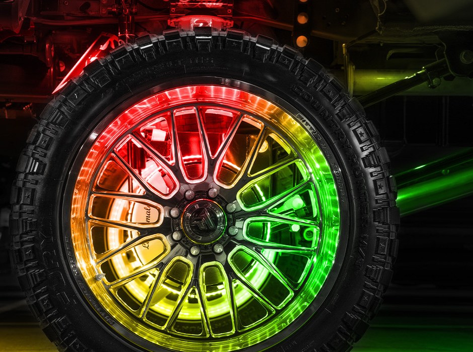 Large off-road tire with an LED ring glowing red, yellow, and green around the rim