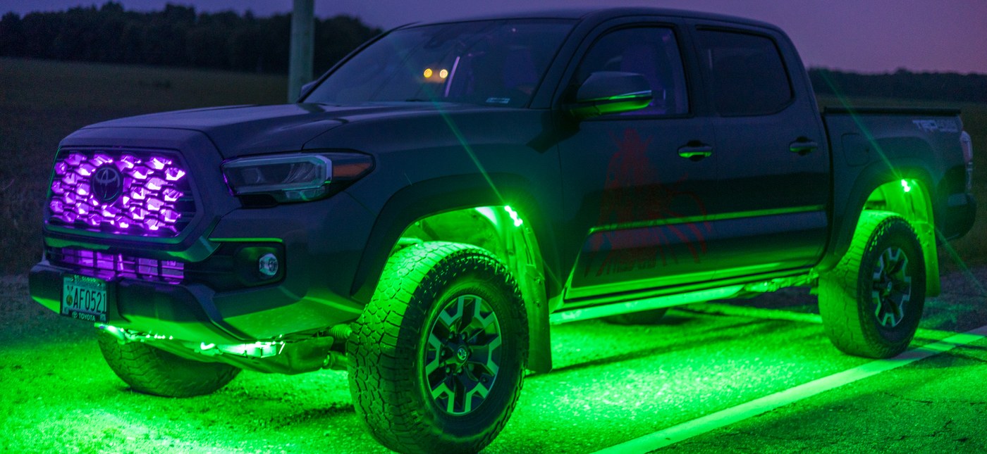 Toyota Tacoma TRD with green rock lights in the wheel wells and a purple-lit grille