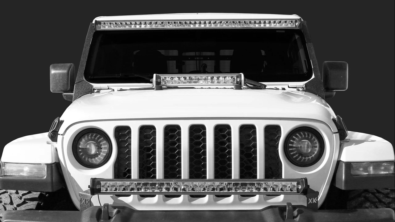 Front of a white Jeep with LED light bars mounted on the roof header, the hood, and the front bumper